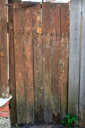 Brown wooden door made of planks in old fence. Old fence. Close-upの写真素材