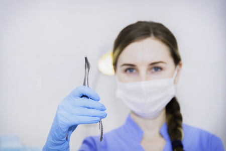 Female doctor in mask with nasal mirror in the hand in glove on hospital backgroundの写真素材
