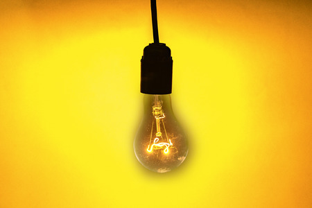 Old vintage bulb light on the yellow backgroundの写真素材