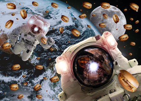 Astronauts in outer space with cheseburgers on the Earth and the Moon on the background. Elements of this image furnished by NASAの写真素材