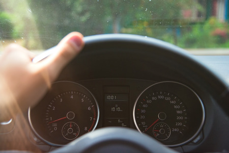 Car speedometer with 0 km on it and hand on the stearwheel under morning sunset lightsの写真素材