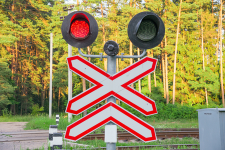 Old semaphore with red light in the forest at eveningの写真素材