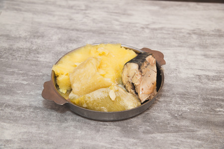 Cheap food in a poor country. Boiled mackerel, mashed potatoes and boiled squash in metal plate on...