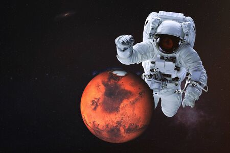 Giant astronaut near Mars planet of Solar system. Science fiction wallpaper. Elements of the image are furnished byの写真素材