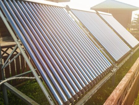 Vacuum collectors on the backyard. Solar panels for water heating with lens flare.