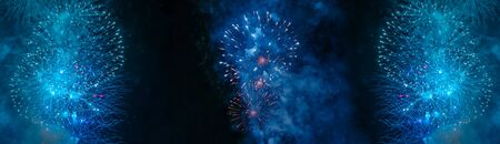 Blue and white fireworks with smoke over the black sky. Low key exposure. Selective focus.の写真素材