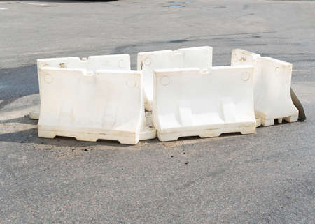 White plastic barrier blocks around the defect on the asphalt due the maintenance. High quality...