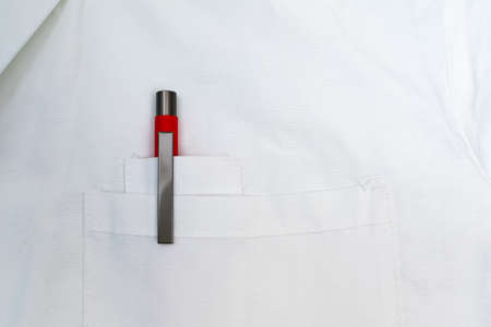 Red pen in the front pocket of the doctors white coat close up.の写真素材