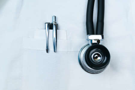 Black pens in the front pocket of the doctors white coat with Stethoscope phonendoscope close up.の写真素材