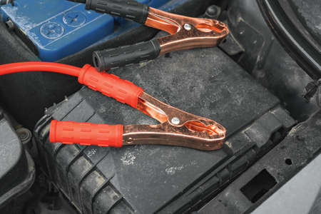 Jump cables on car low power battery. Black and red. Broken car start attempt. Selective focus.の写真素材