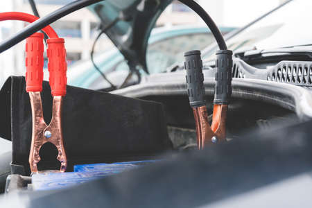 Jump cables on car low power battery. Black and red. Broken car start attempt. Selective focus.の写真素材