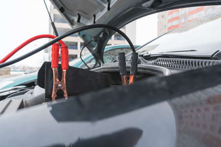 Jump cables on car low power battery. Black and red. Broken car start attempt. Selective focus.の写真素材