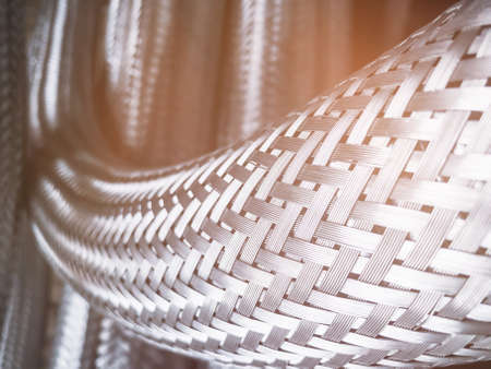Long metal flexible compensator pipes metal texture closeup with lens flare. Selective focus. White...
