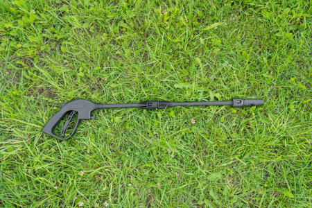 Handle and sprayer of a high-pressure washer on green grassの写真素材