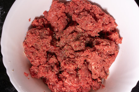 minced meat in a white bowl on a black background closeupの写真素材