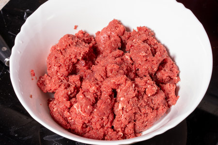 A close-up view of a bowl filled with fresh ground meat. The reddish-pink meat has a coarse texture, suitable for preparing burgers, meatballs, or other recipes requiring minced meat.の写真素材