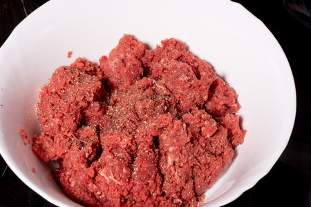 minced meat in a white bowl on a black background close upの写真素材