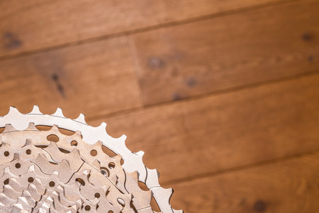 Close-up of a multi-sprocket bicycle cassette resting on wood flooring, showing gear progression and hub interface.の写真素材
