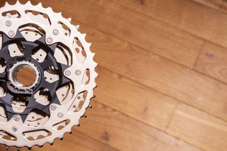 Close-up of a multi-sprocket rear cassette mounted on a bicycle hub, partially visible on wood...