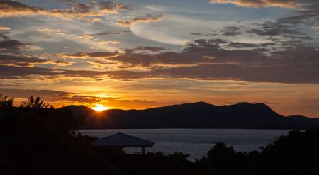 The sun rises over the mountains from the sea front, Thailandの写真素材