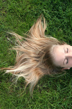 Beautiful woman lying on the grass with her hair fanning outの写真素材