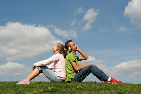 Couple sitting on grass and listening to musicの写真素材