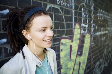 Woman leaning against brick wall with graffiti