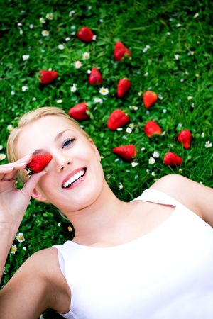 Young woman lying on grass with strawberriesの写真素材