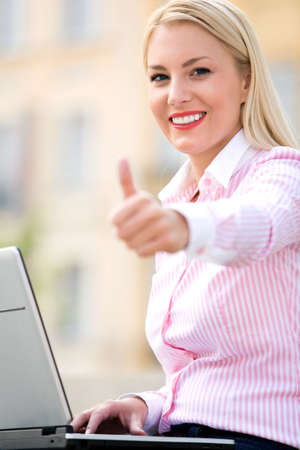 Woman with laptop and thumbs upの写真素材