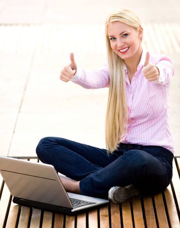 Woman with laptop and thumbs upの写真素材