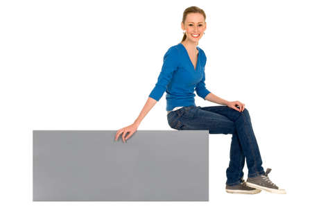 Teenage girl sitting on a blank signの写真素材