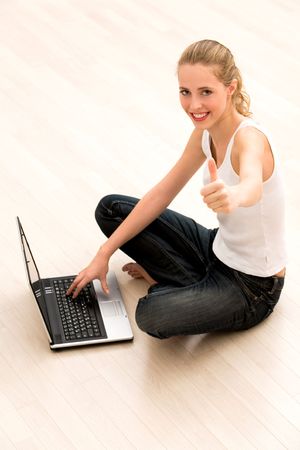 Girl with thumbs up using laptopの写真素材