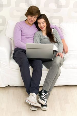 Young couple using laptop on couchの写真素材
