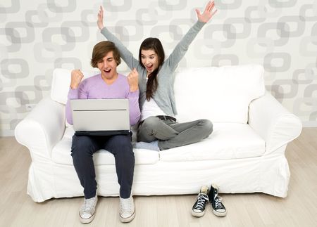 Young couple using laptop on couchの写真素材