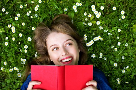 Woman lying on grass with bookの写真素材