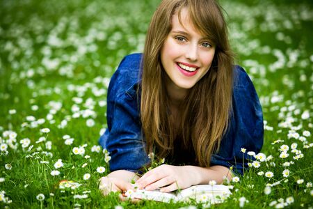 Woman lying on grass with bookの写真素材