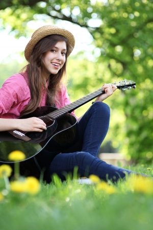 Woman playing guitar in parkの写真素材