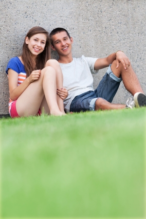 Teenage couple sitting on grassの写真素材