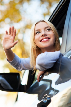 Woman waving from car windowの写真素材