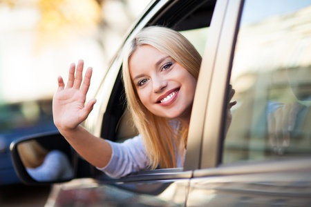 Young woman waving from car window