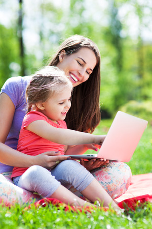 Mother and daughter using laptop outdoorsの写真素材