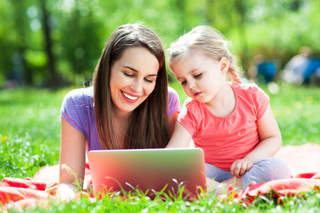 Mother with child using laptop outdoorsの写真素材