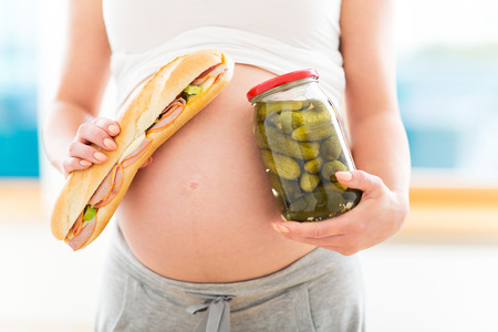 Pregnant woman with sandwich and jar of picklesの写真素材
