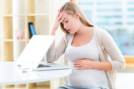 Tired pregnant woman workingの写真素材