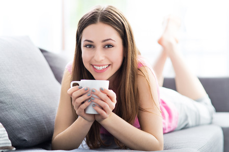 Woman drinking coffee on sofaの写真素材