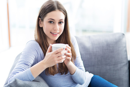 Woman drinking coffee on sofaの写真素材