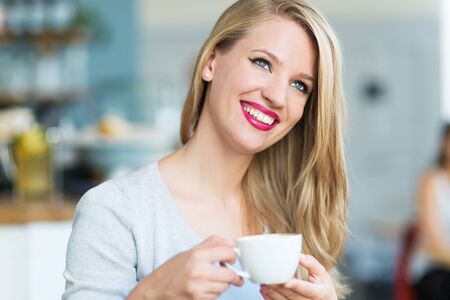 Woman drinking coffee at a cafeの写真素材