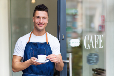 Proud young cafe owner in doorwayの写真素材