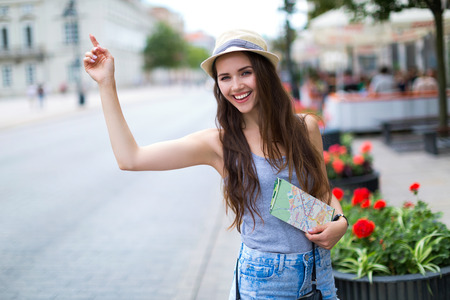 Tourist waving for a taxi on city streetの写真素材