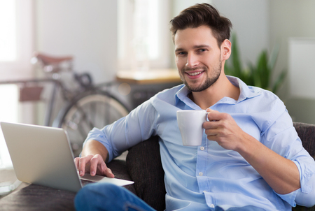 Man sitting on couch with laptopの写真素材